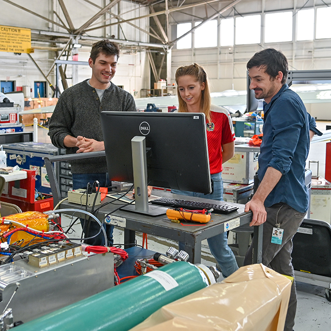 Gordon Novak, Samantha Lee, and Martin Breitenlechner work on the stratospheric chemical ionization mass spectrometer (CIMS) instrument during SABRE 2022 in the NASA WB-57 hangar at Ellington Field.